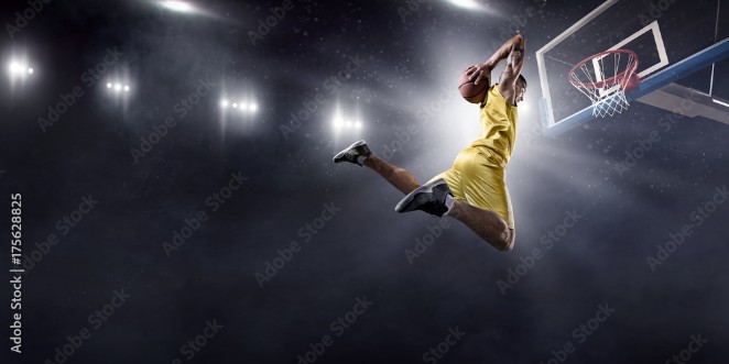 Picture of Basketball player makes slam dunk on big professional arena Player flies through the air with the ball Player wears unbranded clothes